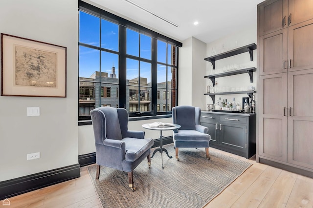 sitting room with recessed lighting, a dry bar, and light wood finished floors