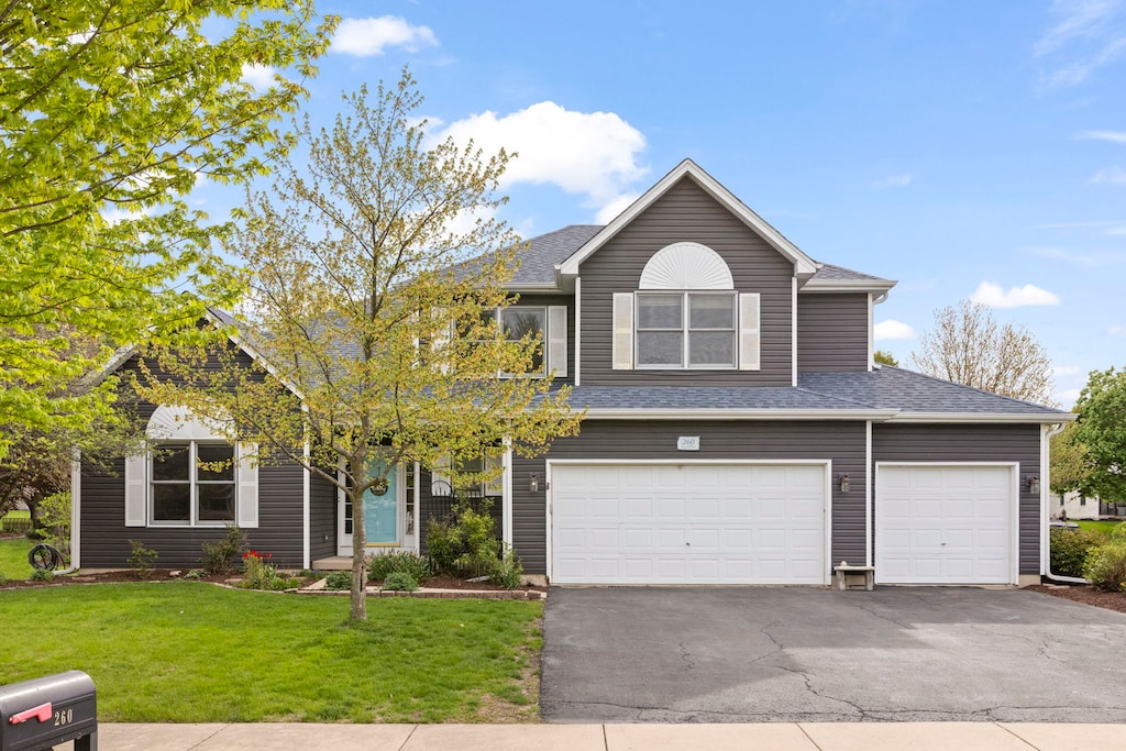 260 Isleview Dr, Oswego, IL 60543 - view of front of house featuring an attached garage, a front lawn, roof with shingles, and aphalt driveway