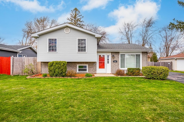 tri-level home with brick siding, a front lawn, and fence