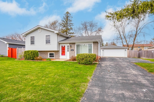 tri-level home featuring fence, a garage, a front lawn, and brick siding