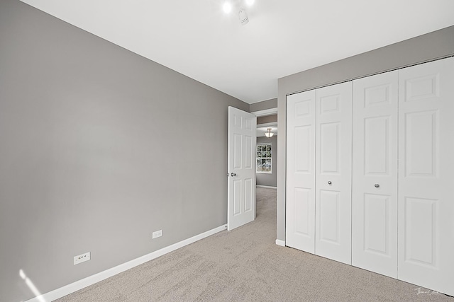 unfurnished bedroom featuring carpet floors, baseboards, and a closet