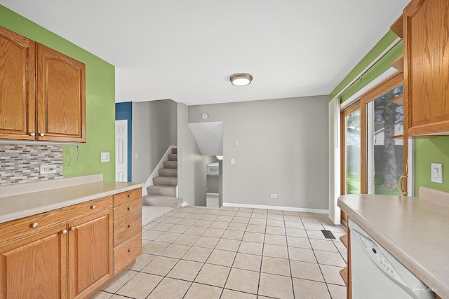 kitchen with decorative backsplash, dishwasher, light countertops, brown cabinets, and light tile patterned floors