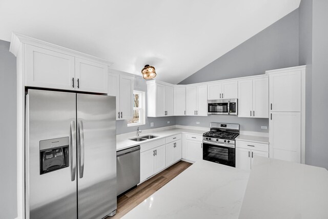 1409 172nd St, Hazel Crest, IL 60429 - kitchen featuring white cabinets, appliances with stainless steel finishes, wood finished floors, a sink, and lofted ceiling