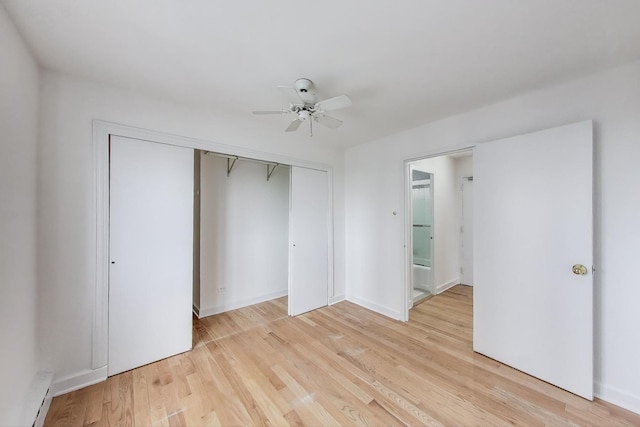 unfurnished bedroom featuring baseboard heating, light wood finished floors, a ceiling fan, baseboards, and a closet