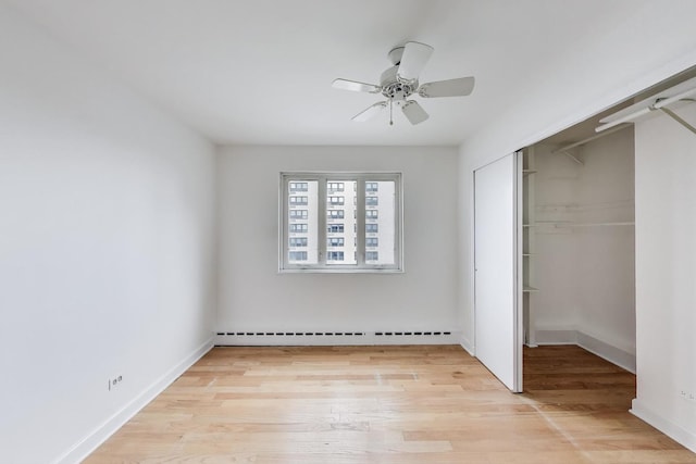 unfurnished bedroom with a closet, a ceiling fan, baseboards, a baseboard radiator, and light wood finished floors