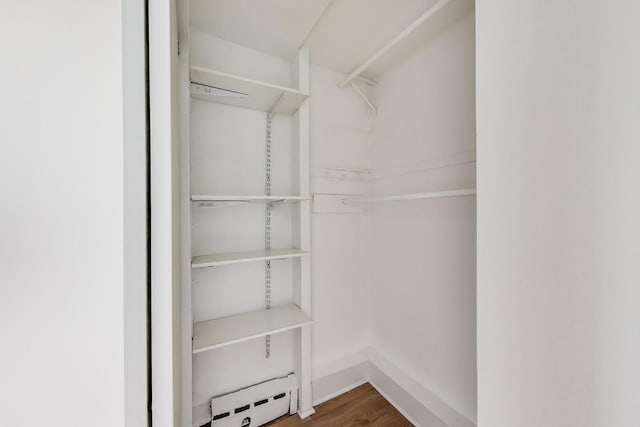 spacious closet featuring wood finished floors and a baseboard heating unit