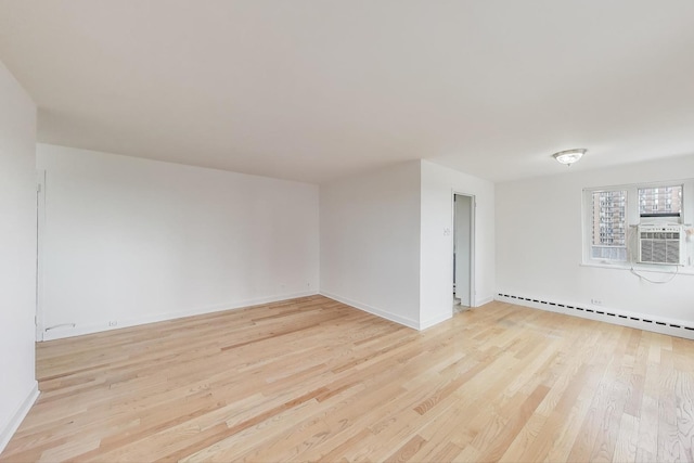 spare room featuring light wood-style floors, baseboards, a baseboard heating unit, and cooling unit