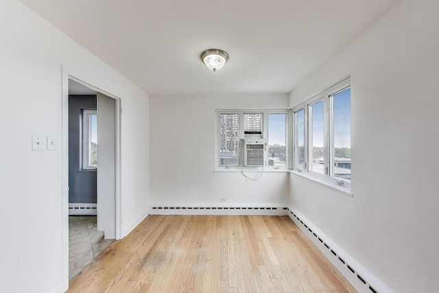 unfurnished room featuring baseboards, a baseboard heating unit, baseboard heating, and light wood-type flooring