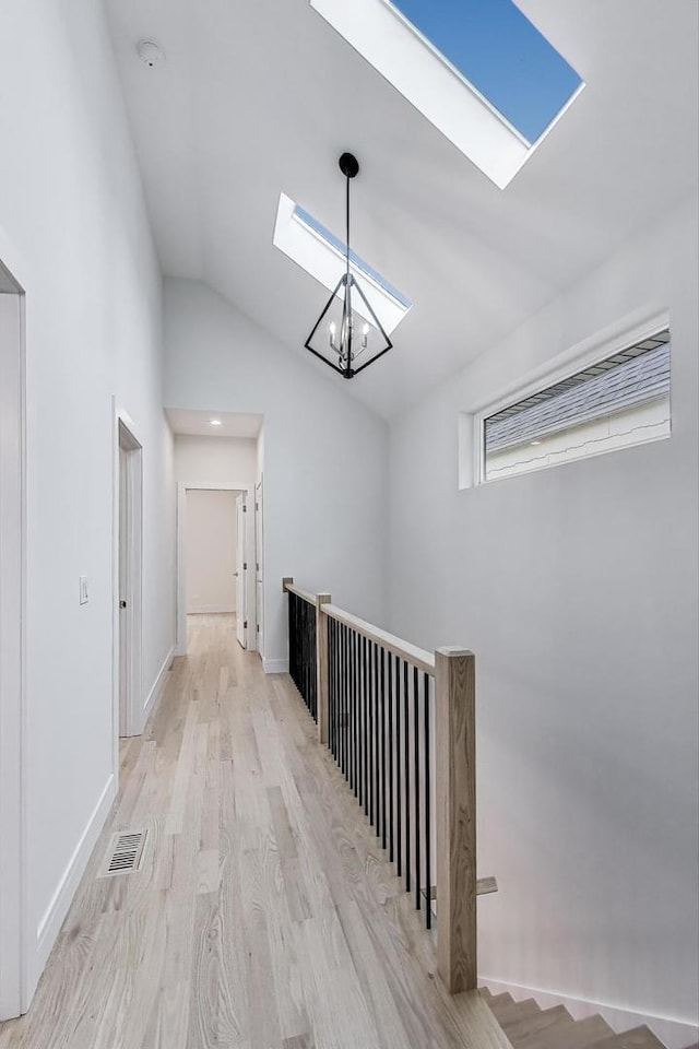 3242 N Kostner Ave, Chicago, IL 60641 - corridor featuring visible vents, vaulted ceiling with skylight, light wood-type flooring, an upstairs landing, and a chandelier