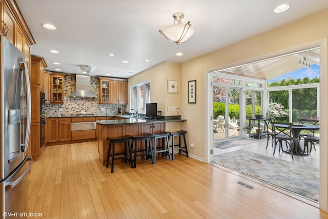 1831 Ellendale Dr, Northbrook, IL 60062 - kitchen featuring appliances with stainless steel finishes, wall chimney exhaust hood, brown cabinetry, a peninsula, and a breakfast bar area