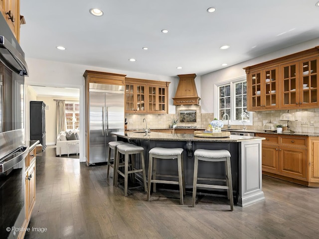 116 Springlake Ave, Hinsdale, IL 60521 - kitchen with a kitchen island with sink, a breakfast bar, stainless steel appliances, premium range hood, and light stone countertops