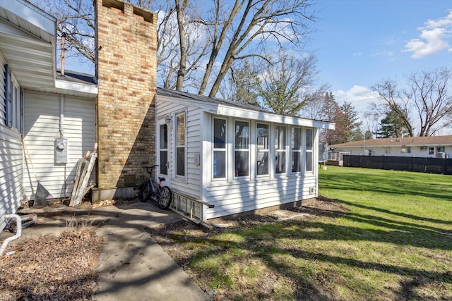 313 W S St, Pearl City, IL 61062 - view of side of property featuring fence, a sunroom, a lawn, and a chimney
