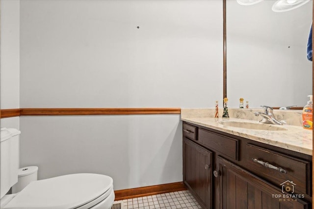 half bath featuring tile patterned flooring, toilet, vanity, and baseboards