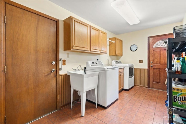 laundry area with wainscoting, light tile patterned floors, cabinet space, washing machine and dryer, and wood walls