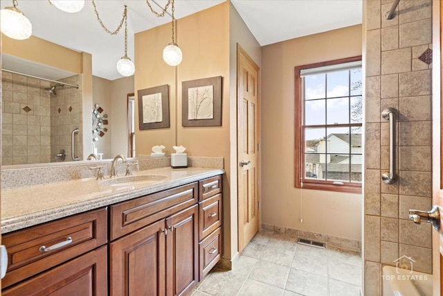 full bath featuring baseboards, vanity, visible vents, and tiled shower
