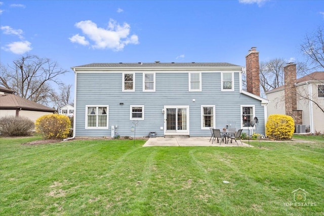 back of property with a yard, a chimney, a patio area, and central AC