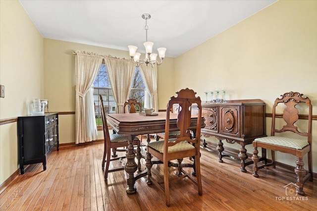 dining space with a chandelier, light wood-style flooring, and baseboards