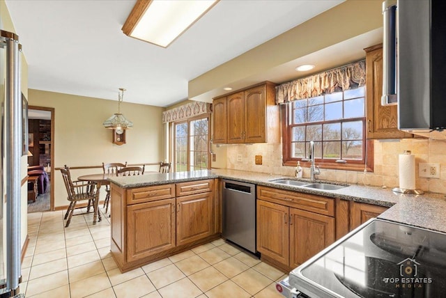 kitchen with stainless steel appliances, a peninsula, a sink, and brown cabinets
