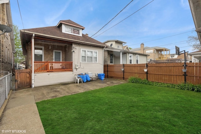rear view of house featuring a lawn, a fenced backyard, a gate, and a shingled roof