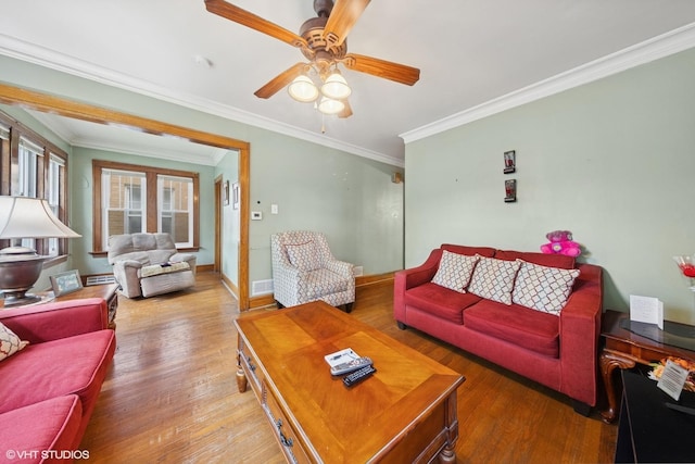 living area with a ceiling fan, baseboards, ornamental molding, and light wood-style flooring
