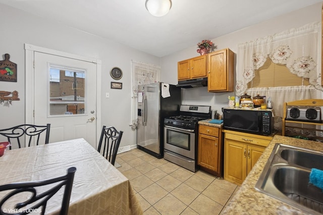 kitchen featuring light countertops, under cabinet range hood, a sink, appliances with stainless steel finishes, and light tile patterned floors