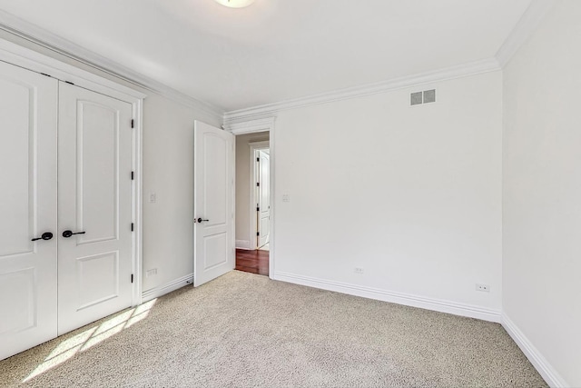 unfurnished bedroom featuring carpet flooring, baseboards, crown molding, and a closet