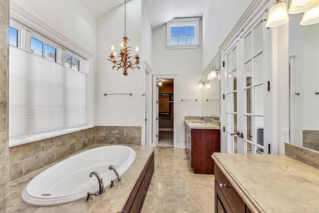 full bathroom with high vaulted ceiling, plenty of natural light, vanity, a bath, and a chandelier