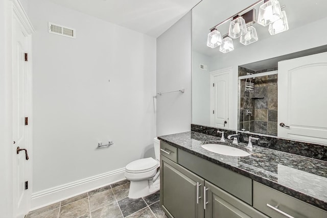 full bath featuring baseboards, vanity, a stall shower, toilet, and stone finish flooring