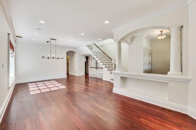 unfurnished living room with wood finished floors, stairway, arched walkways, crown molding, and baseboards