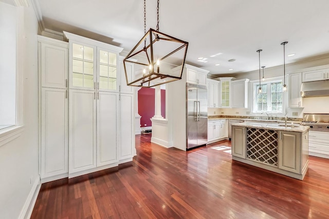 kitchen featuring appliances with stainless steel finishes, exhaust hood, glass insert cabinets, dark wood finished floors, and white cabinetry
