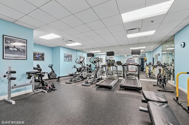 exercise room featuring a drop ceiling and baseboards