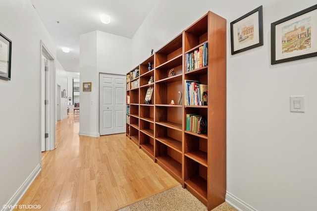 hall featuring light wood-style flooring and baseboards