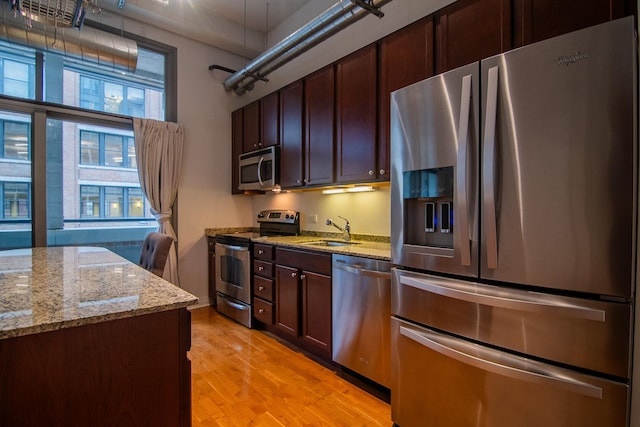 565 W Quincy St Unit 510, Chicago, IL 60661 - kitchen with dark brown cabinets, a sink, light wood finished floors, appliances with stainless steel finishes, and light stone countertops