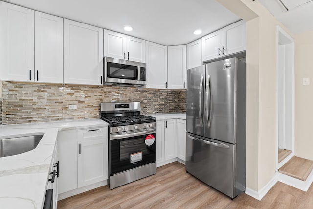 7730 Virginia Ct, Willowbrook, IL 60527 - kitchen featuring light wood-style floors, light stone countertops, white cabinets, appliances with stainless steel finishes, and decorative backsplash