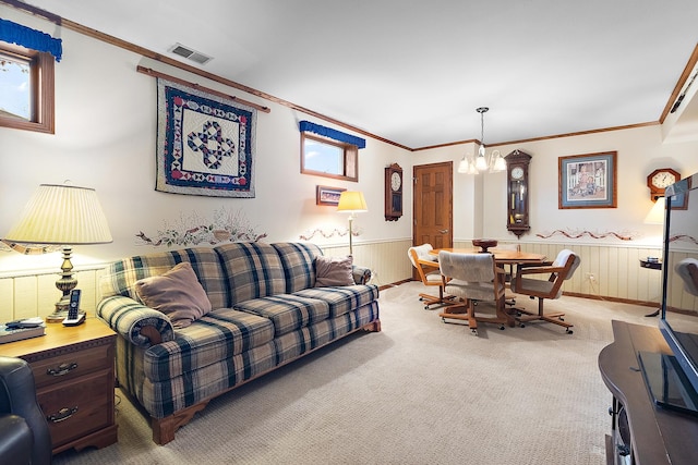 living room with a chandelier, crown molding, visible vents, and a wainscoted wall