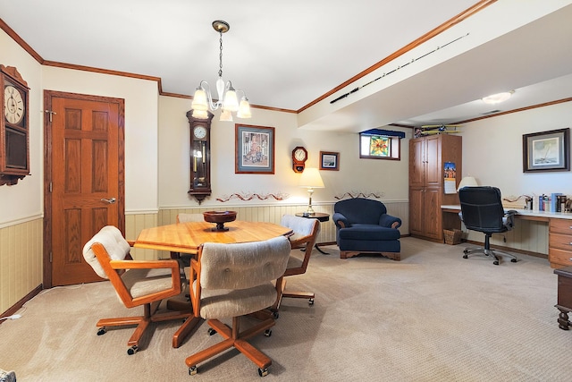 dining area featuring wainscoting, a chandelier, light colored carpet, and crown molding