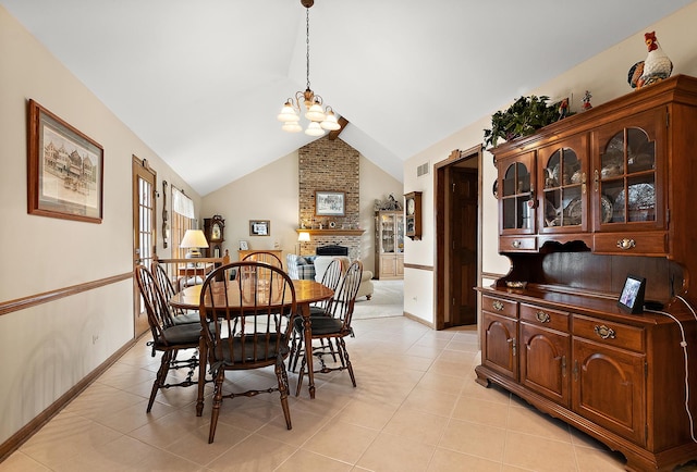 dining space with vaulted ceiling, an inviting chandelier, light tile patterned floors, and a fireplace