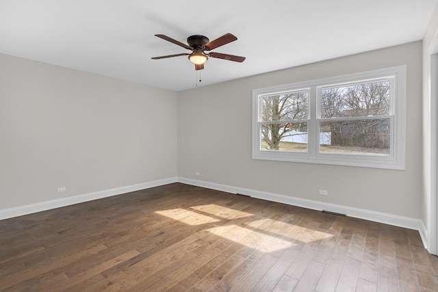empty room with ceiling fan, baseboards, and dark wood finished floors