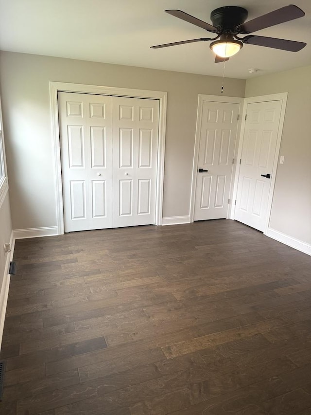 unfurnished bedroom with ceiling fan, a closet, baseboards, and dark wood-style flooring