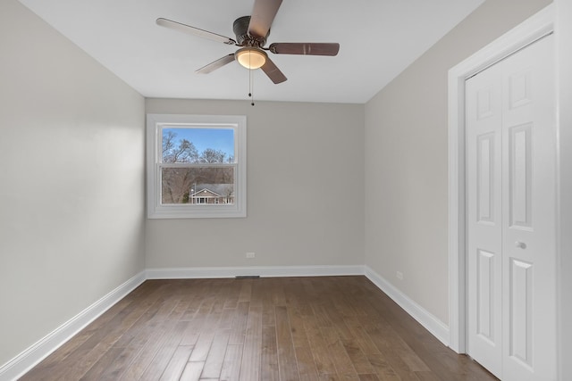 unfurnished bedroom featuring baseboards, a ceiling fan, and dark wood finished floors