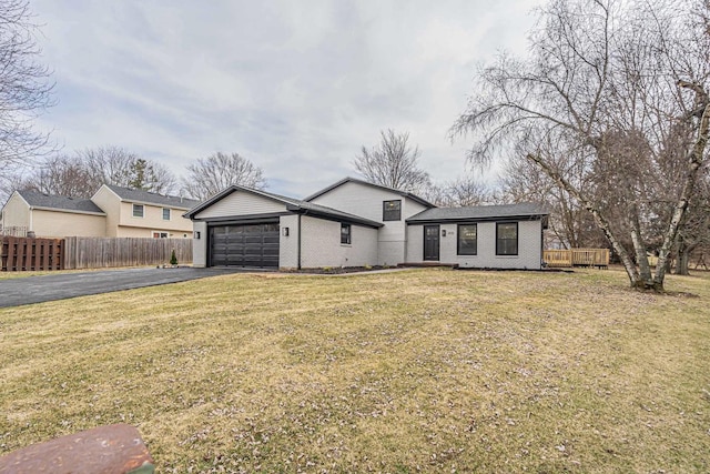 view of front facade featuring a garage, a front yard, fence, brick siding, and driveway