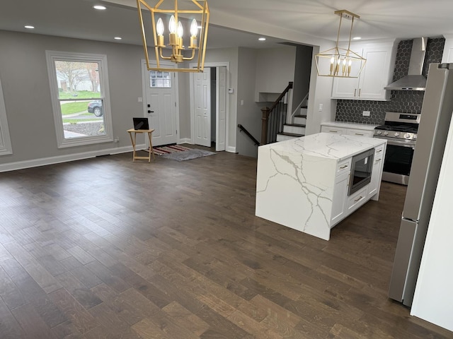 kitchen featuring gas range, wall chimney exhaust hood, a notable chandelier, and built in microwave