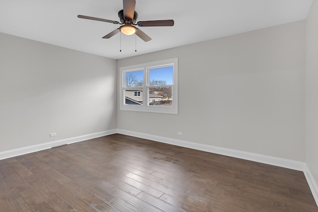 empty room featuring dark wood finished floors, baseboards, and ceiling fan
