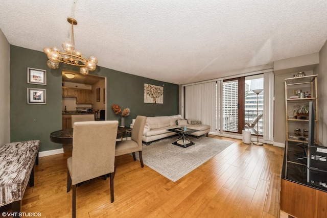 living room featuring a chandelier, light wood finished floors, a textured ceiling, and baseboards
