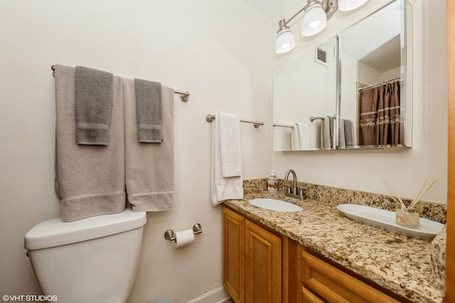 bathroom featuring toilet, double vanity, a sink, and visible vents