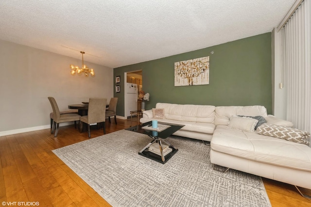 living room with a chandelier, a textured ceiling, baseboards, and wood finished floors
