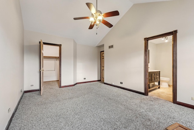 unfurnished bedroom with carpet floors, baseboards, high vaulted ceiling, connected bathroom, and a spacious closet