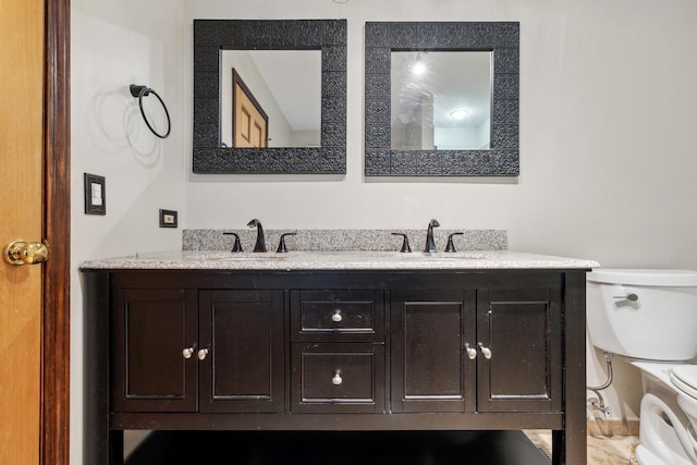 bathroom featuring toilet and double vanity