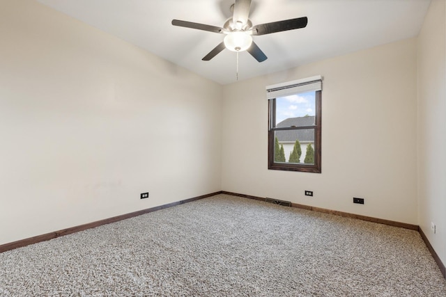 spare room featuring light carpet, a ceiling fan, and baseboards