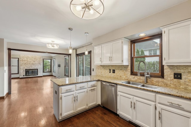kitchen featuring dishwasher, a sink, a peninsula, a chandelier, and white cabinetry